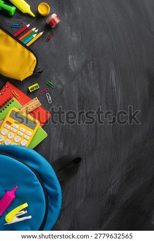 Back to school scene with colorful backpack, pencils, calculator, notebooks and other stationery arranged on a chalkboard background ideal for education, learning and classroom themed projects