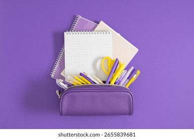 Back to school. A stack of notepads and notebooks and a purple pencil case filled with pens and pencils. School educational theme.