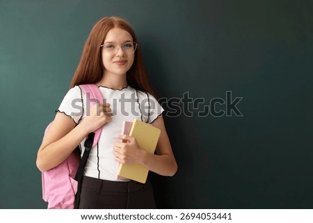 Back to school. Student with backpack and books near green chalkboard indoors, space for text