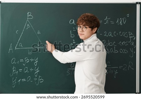 Back to school. Student doing math on chalkboard indoors