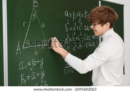 Back to school. Student doing math on chalkboard indoors