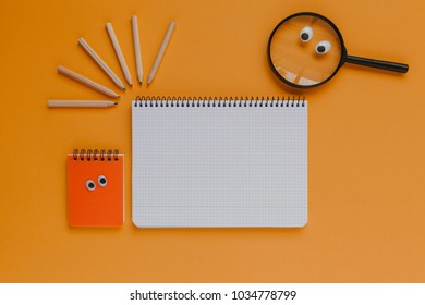 Back to school stuff, notebook with copy space in the middle. Orange background.