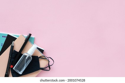 Back To School. School Supplies And A Backpack On Pink Background With A Protective Mask And Antibacterial Spray. Banner