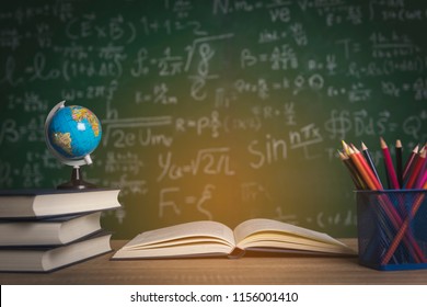 Back to school supplies. Books and blackboard on wooden background - Shutterstock ID 1156001410