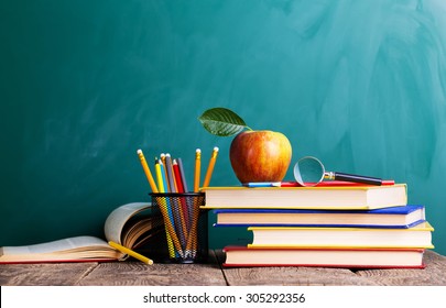 Back To School Supplies. Books And Blackboard On Wooden Background