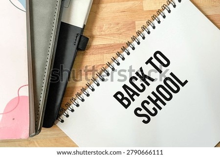 Back To School text written on spiral notebook page with office stationery on wooden desk. New semester and education concept.