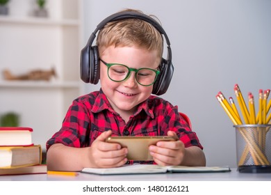 Back to school. Thinking child doing homework online with smartphone. Pupil in headphones. Learn English. Innovation teacher concept. Addicted kid gaming. Boy listening to music, playing