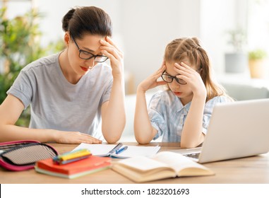 Back To School. Unhappy Child And Adult Are Sitting At Desk. Girl Doing Homework Or Online Education.