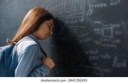 Back to school. Unhappy teenager indoors. Girl is learning in class on background of blackboard. - Powered by Shutterstock