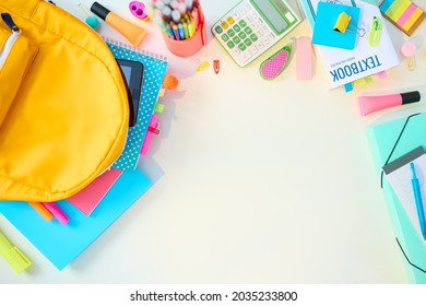 Back to school. Upper view of white desk with workbooks, stationary, textbook and backpack at school child room in sunny day.