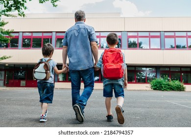 Back to school. View from the back of a happy dad escorts his sons schoolchildren to school. Parental care for children