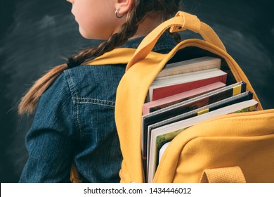 Back to school. Back view of young girl ready to study, with open backpack full with books.
