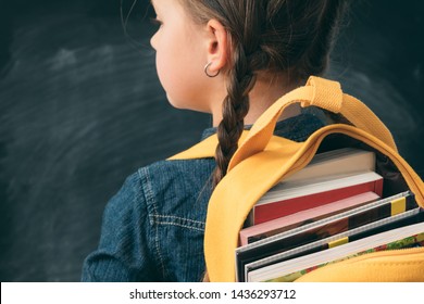 Back to school. Back view of young girl with open backpack fully stuffed with books. - Powered by Shutterstock