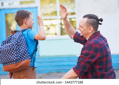 Back to school.Happy father and son are welcome before elementary school. parent meets a child from elementary school.The student goes to school with a backpack.The first day of autumn.clap your hands