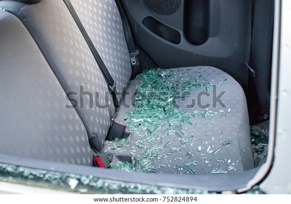 The back\
seat of a vandalized car with broken smashed glass covering the\
seat.  The car was broken into and\
stolen.