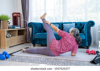 Back Of Senior Woman Doing Exercise Stretching Legs With Side-lying Leg Lift, Workout  Yoga Pose At Home