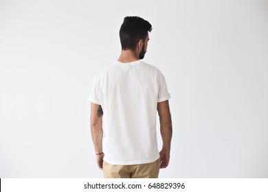 Back Shot Of Handsome Bearded Man With Fresh Haircut And Tattooed Arms Posing On Isolated Wall Mockup In White Simple Blank Tshirt Ready For Designs 