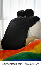 Back Shot, A Loving Asian Teenage Gay Men Couple Sits Together, Relaxes In Living Room, Hand Around His Boyfriend Shoulder. LGBT Couple.