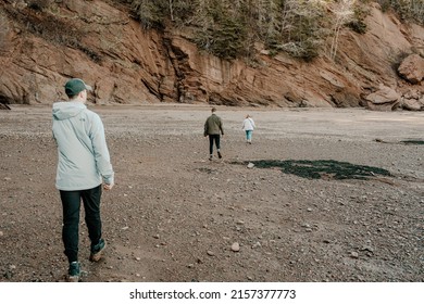 A Back Shot Of Three People Walking In The Hopewell Rocks Provincial Park During Daytime In New Brunswick, Canada