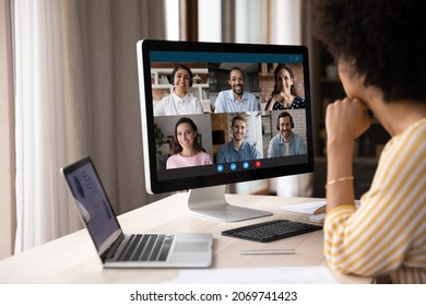 Back shoulder view concentrated young African American businesswoman looking at computer monitor, holding video conference online call with multiracial colleagues, distant working communication. - Powered by Shutterstock