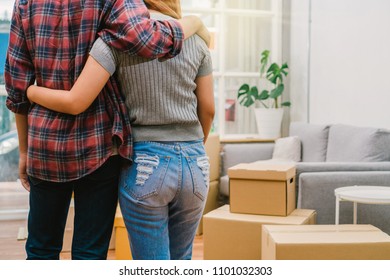 Back Side Of Asian Young Couple Hugging Together Over The Big Cardboard Box And Sofa When Moving In New Home, Moving And House Hunting Concept