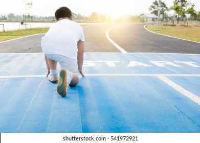 Back Side Of Fit And Confident Fat Boy In Starting Position Ready For Running. Kid Athlete About To Start A Sprint With Bright Sunlight.