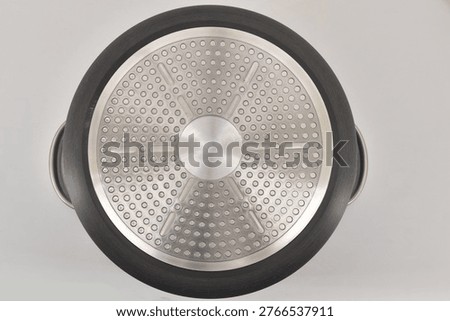 Back side of frying pan with induction compatible base isolated on white background.