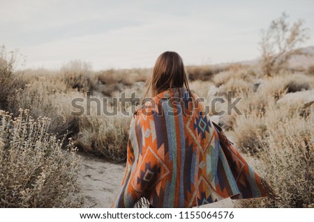 Back side of  hipster traveler girl with windy hair in gypsy look in desert nature.  Artistic photo of young hipster traveler girl in gypsy look, in Coachella Valley in a desert valley in Southern Cal
