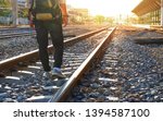 Back side of man with backpack walking away on railroad with flare light on faraway destination, patience and trying step forward to goal or successful concept 