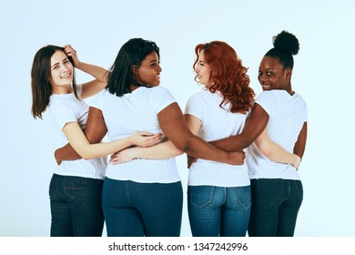 Back Side Of Multiracial Group Of Women Standing In Line In A Half Turn To Camera , Wearing Casuals, Hugging Together On White Background.