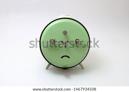 Back side of an old Junghans mechanical alarm clock. It appears to show a sad face.