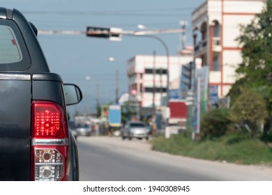 Back Side Of Pick Up Car Black Color On The Asphalt Road With Open Brake Light. Traffic Condition In The City At Day Time.