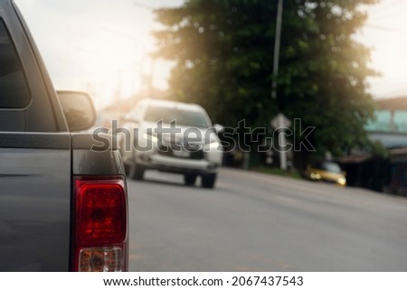 Back side of pick up car gray color on the asphalt road. With traffic conditions and hot sun during the day and other cars driving opposite lens.