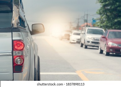 Back Side Of Pick Up Car Silver Color On The Asphalt Road With Open Brake Light. With Traffic Conditions And Hot Sun During The Day.