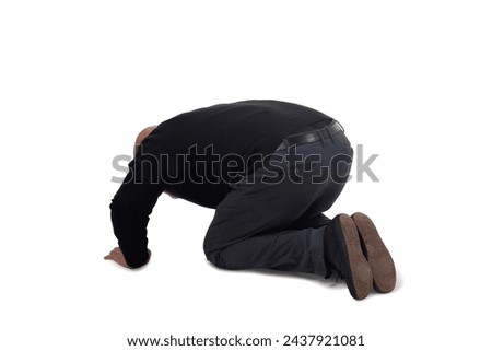 back side view of a man on his knees staring at the ground on white background