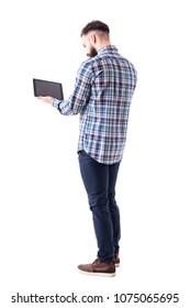 Back side view of young business man using and working on tablet computer. Full body length isolated on white background.