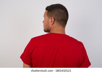 The Back Side View Of A Young Handsome Cucasian Man Wearing Red Shirt Standing Against White Background Studio Shoot.