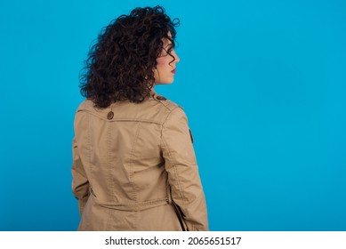 The Back Side View Of A Young Pregnant Arab Woman Standing On Blue Studio Background  . Studio Shoot.