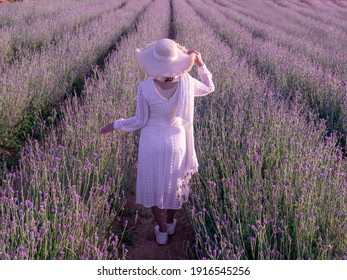 Back side of woman in white dress and hat in beautiful Lavender field.