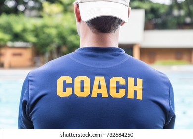 back of a sport coach's blue shirt with the yellow Coach word written on it; good background for sport or coaching theme