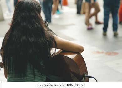 back of a street musician girl , playing guitar to chase her dream