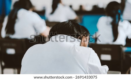 Back of students reading exam answer sheets exercises in classroom of school with headache and stress