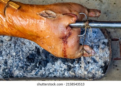 Back of the suckling pig on a spit over wood and charcoal.