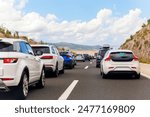 Back tail view of many cars stuck in row at highway road traffic jam warm hot sunny day at southern Europe. Automobile accident vehicle rush hour collapse. Transportation vacation seasonal stuck