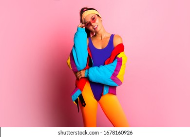 Back In Time 90s 80s. Stylish Girl In Retro Colourful  Vintage Coat, Orange Leggings, And Purple Body, Fashion Trends, Entertainment. 80's Fashion Woman Over Pink Background. Beautiful Athletic Girl.