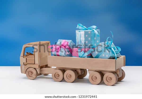 In back of\
toy car are festive boxes in blue with white polka dots and pink\
packaging. Surprises for Christmas, New Year, birthday, Valentine\'s\
Day. Copy space. Blue\
background.