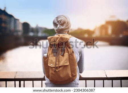 Back, travel and a tourist man by a lake in the city for adventure or a journey of self discovery abroad. Bridge, view and blurred background with a male traveler standing outside in an urban town