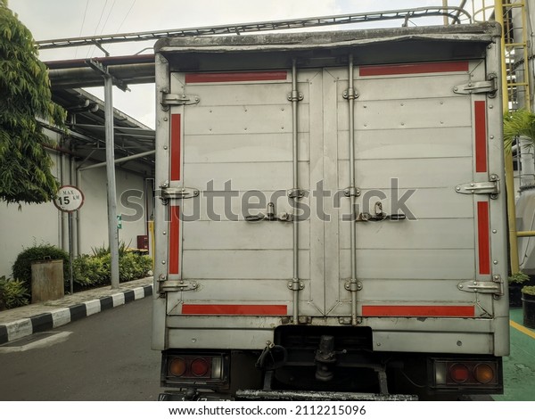 Back of a truck with\
reflective red warning with road mark and speed limit sign in a\
industrial place