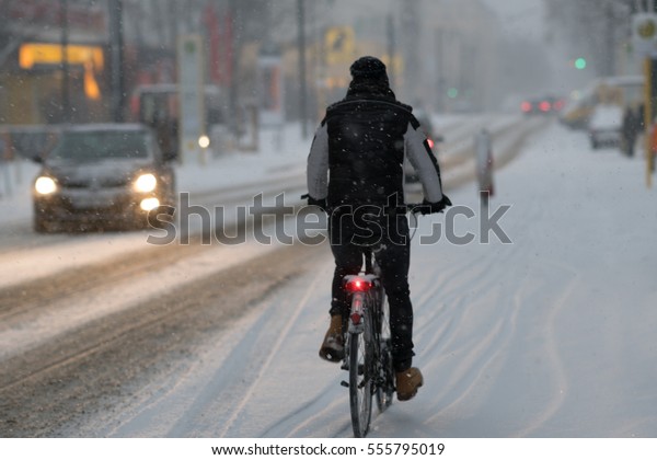 Back turned cyclist\
riding bike in snow