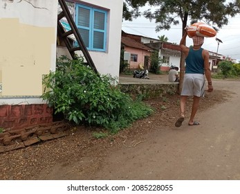 Back View Of 30 To 40 Year Old Indian Man Carrying Grain Sack Or Grains Bag On His Head And Walking Towards His House . Beautiful And Simple Indian Village Houses ,Picture Captured At Shelakewadi.